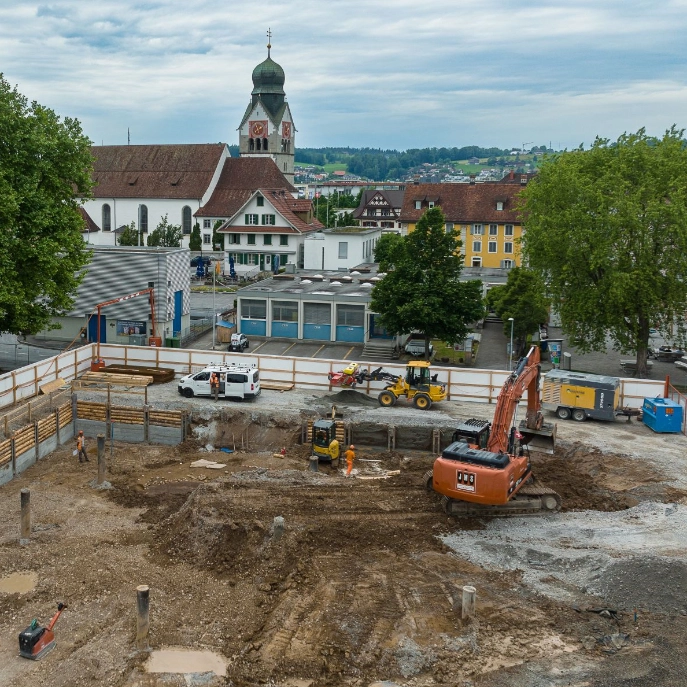 Baustelle Schulhaus Sternmatt mit Bagger und Arbeitenden