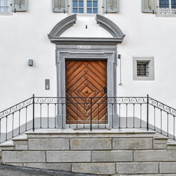 Eingangstür mit Dekorelementen und zweiseitige Treppe im Vordergrund