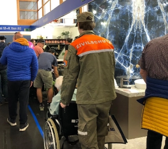 Zivilschützer unterstützt Frau im Rollstuhl