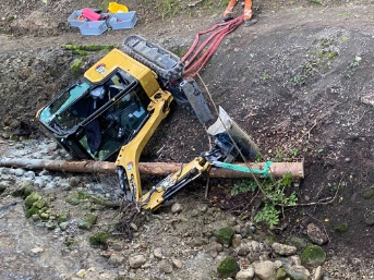 Bagger kippt zur Seite und landet im Bachbett 