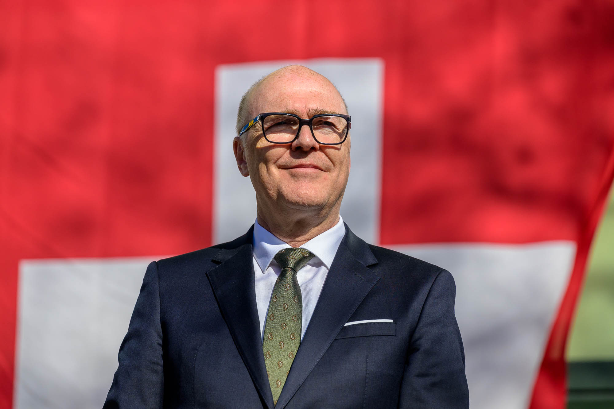 Bundesrat Martin Pfister steht stolz vor der Schweizer Fahne